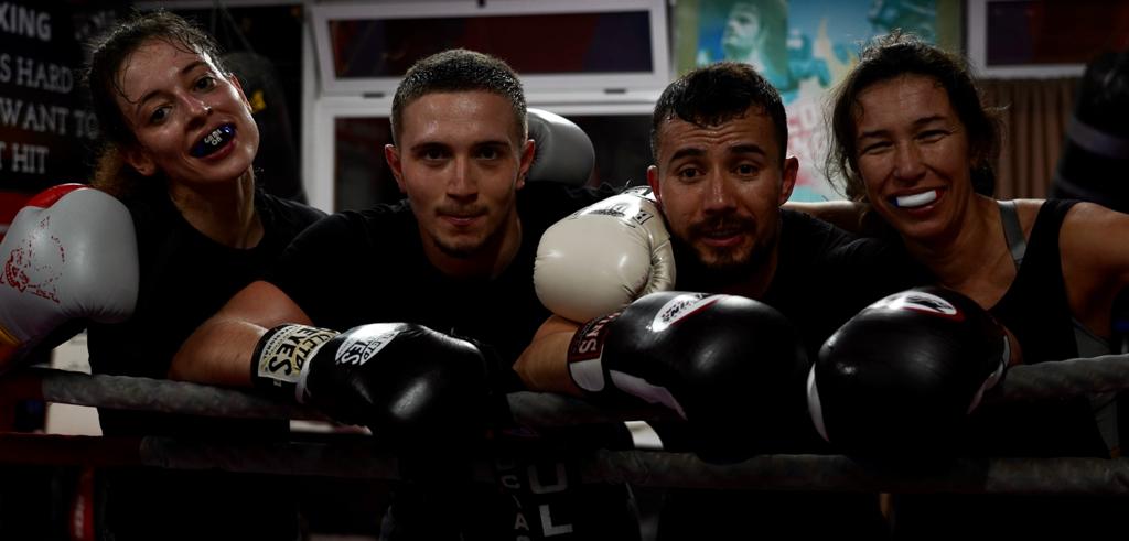 Fotografia ilustrativa: quatro atletas de boxe junto ao ringue.
